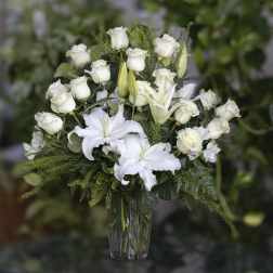 White roses and lilies arranged in a clear glass vase