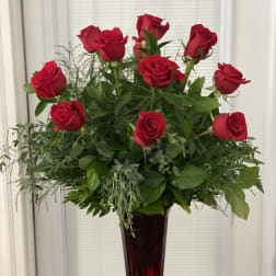 Red roses arranged in a tall burgundy vase