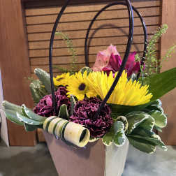 Basket arrangement with yellow gerbera daisies and purple carnations