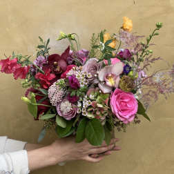 Handheld bouquet of pink, purple, and burgundy flowers