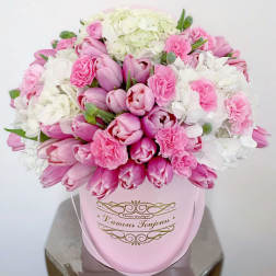 Round pink hatbox filled with pink tulips, pink carnations, and white hydrangeas.