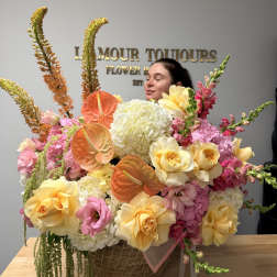 Large pastel flower arrangement in a wicker basket with roses and anthuriums