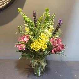 Mixed bouquet in a glass vase with pink, yellow, and purple flowers