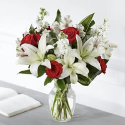 Red roses and white lilies arranged in a clear glass vase
