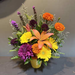 Colorful mixed flower arrangement in a yellow vase with lilies and daisies