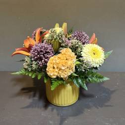 Mixed bouquet in a yellow ribbed vase with orange lilies and yellow blooms