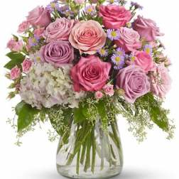 Bouquet of pink and lavender roses with white hydrangea in a glass vase
