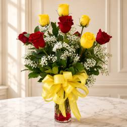 Bouquet of red and yellow roses in a clear glass vase with a yellow ribbon
