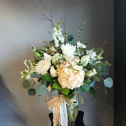 Cream and white bouquet in a clear glass vase with ribbon