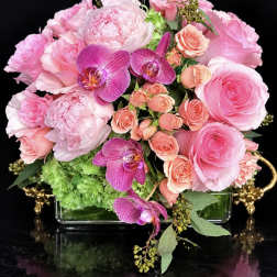 Pink roses and orchids arranged in a glass vase with green hydrangea
