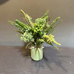 Green floral arrangement in a textured vase with a ribbon