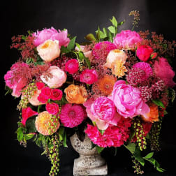 Large pink and peach floral arrangement in a stone vase