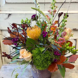 Mixed floral arrangement in a purple vase with peach and orange blooms