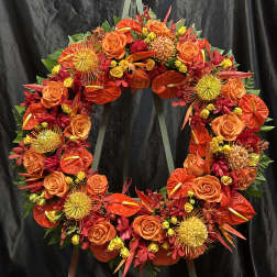 Circular floral wreath with orange and red flowers on a stand