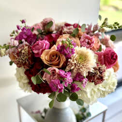 Mixed bouquet of pink, peach, and white flowers in a white vase