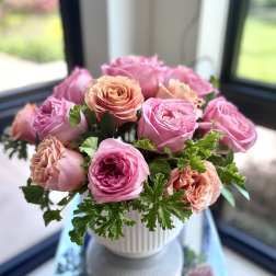 Pink and peach roses arranged in a white vase