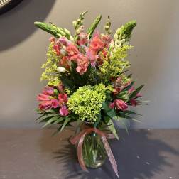 Pink and green mixed flower arrangement in a glass vase with a ribbon
