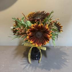 Sunflower bouquet in a dark vase with a yellow ribbon