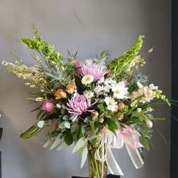 Mixed bouquet of pink and white flowers in a glass vase with ribbon