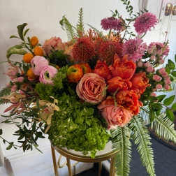 Mixed bouquet with orange and pink flowers in a gold stand