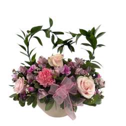 Pink and cream floral arrangement in a round box with a pink bow