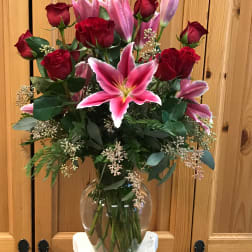 Bouquet of red roses and pink lilies in a clear glass vase