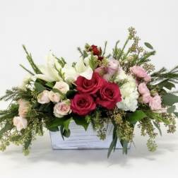 Mixed bouquet in a white wooden box with red, pink, and white flowers