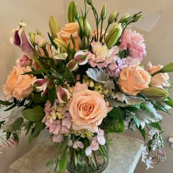 Peach roses and pink lilies in a glass vase