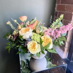 Mixed bouquet of peach and cream roses in a gray vase