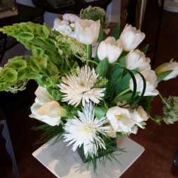 White tulips and spider mums arranged with green blooms in a vase.