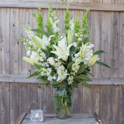 White lilies and snapdragons arranged in a clear glass vase