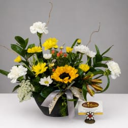 Mixed bouquet with sunflowers, white carnations, and yellow daisies in a black container