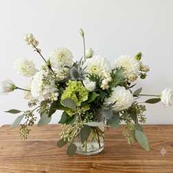 White and green floral arrangement in a clear glass vase