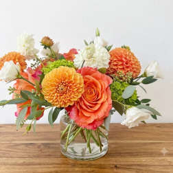 Orange and white flower arrangement in a clear glass vase