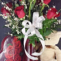 Red roses in a vase with a white ribbon and teddy bear