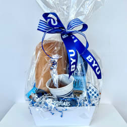 Gift basket with coffee items wrapped in clear cellophane and a blue ribbon