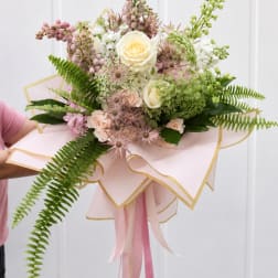Hand-tied bouquet of cream and blush flowers with pink ribbon wrap