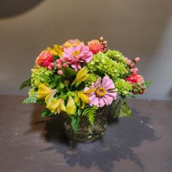 Mixed pink and yellow flowers arranged in a glass vase