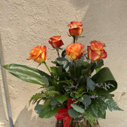 Bouquet of orange-red roses in a glass vase with a red ribbon