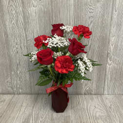 Red roses and carnations in a burgundy vase with a ribbon