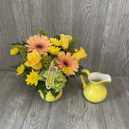 Yellow and peach floral arrangement in a yellow vase beside a matching pitcher
