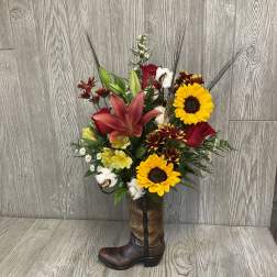 Mixed bouquet with sunflowers, lilies, roses, and cotton in a cowboy boot vase