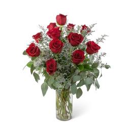 Red roses arranged in a clear glass vase with airy filler