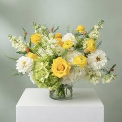 Yellow and white flowers arranged in a clear glass vase