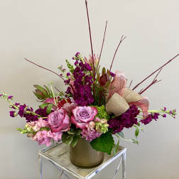 Pink and purple floral arrangement in a vase with ribbon accents