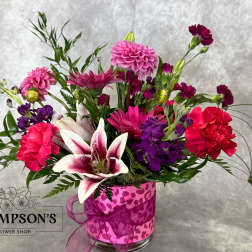 Mixed pink and purple bouquet in a clear glass vase with a ribbon
