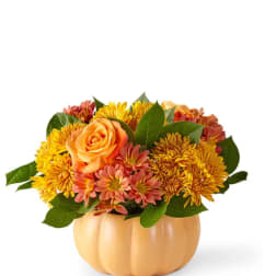 Orange and yellow flower arrangement in a pumpkin-shaped vase
