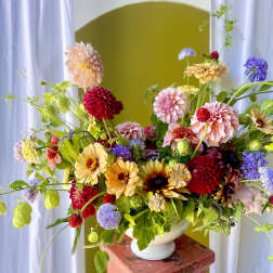 Colorful mixed flower arrangement in a white pedestal vase