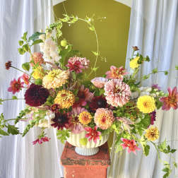 Colorful mixed flower arrangement in a cream vase on a pedestal