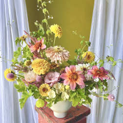 Mixed bouquet of pink, yellow, and white flowers in a white vase